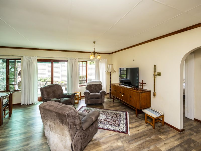 A comfortable living room featuring laminate flooring, an arched entryway, and sliding glass doors that provide access to the outdoor area.