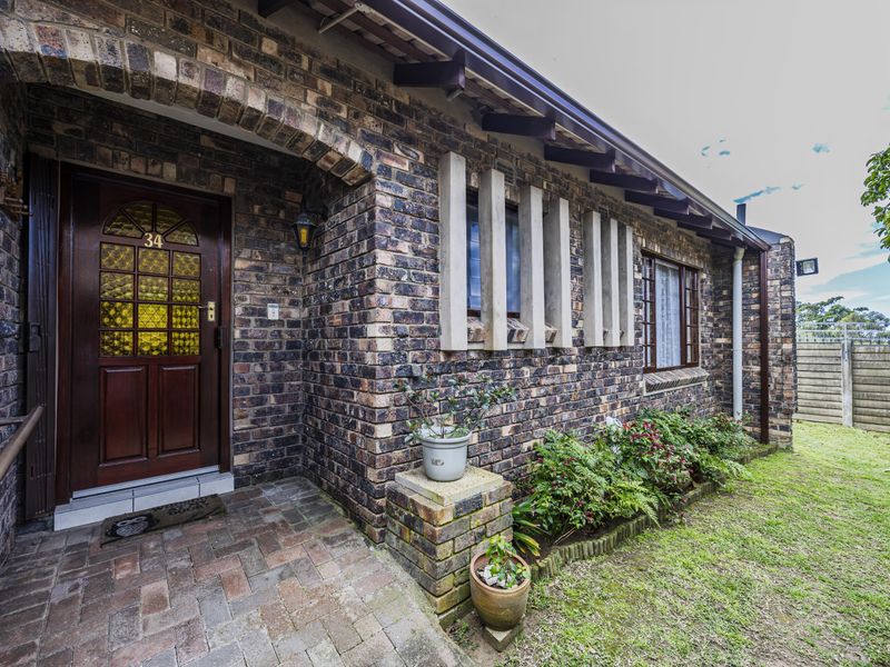 Front entrance of a townhouse featuring a classic face brick facade, timber door with decorative glass, and a paved walkway leading to the entry.