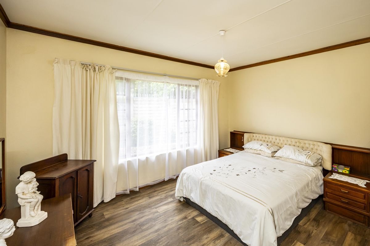 A well-lit bedroom featuring wood-look laminate flooring and a built-in headboard with integrated bedside cabinetry.