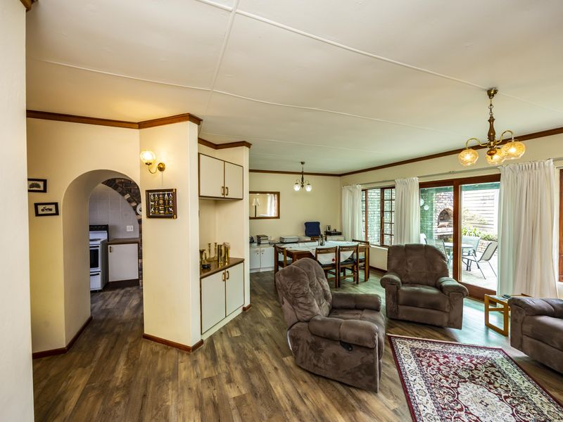 Spacious open-plan living and dining area featuring laminate flooring, an arched entryway, and sliding glass doors providing access to the outdoor patio.