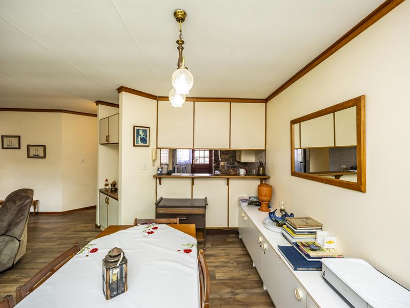 Open-plan dining area featuring laminate flooring, built-in cabinetry, and a convenient pass-through window connecting to the kitchen space.