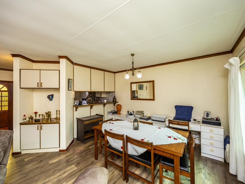 Dining area featuring laminate flooring, built-in cabinetry, and natural light through a window with security bars.