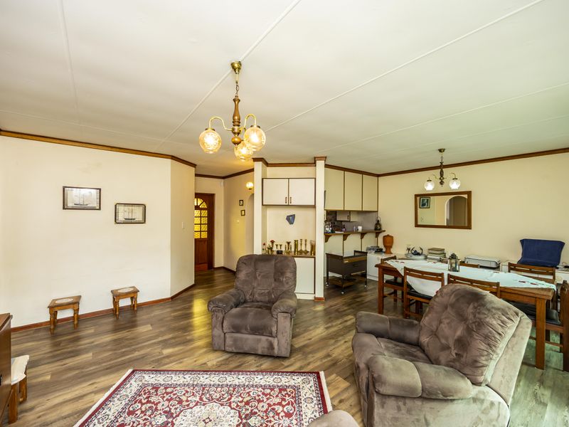 Spacious open-plan living and dining area featuring laminate flooring, neutral walls, and built-in cabinetry, offering a versatile layout for comfortable family living.