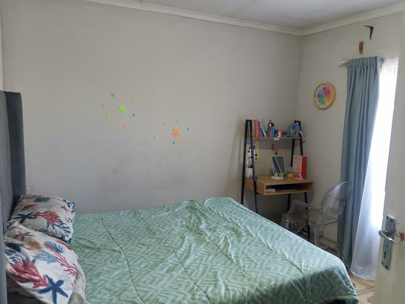A bedroom featuring neutral walls and a window with curtain rails, requiring minor cosmetic updates to improve the overall finish.
