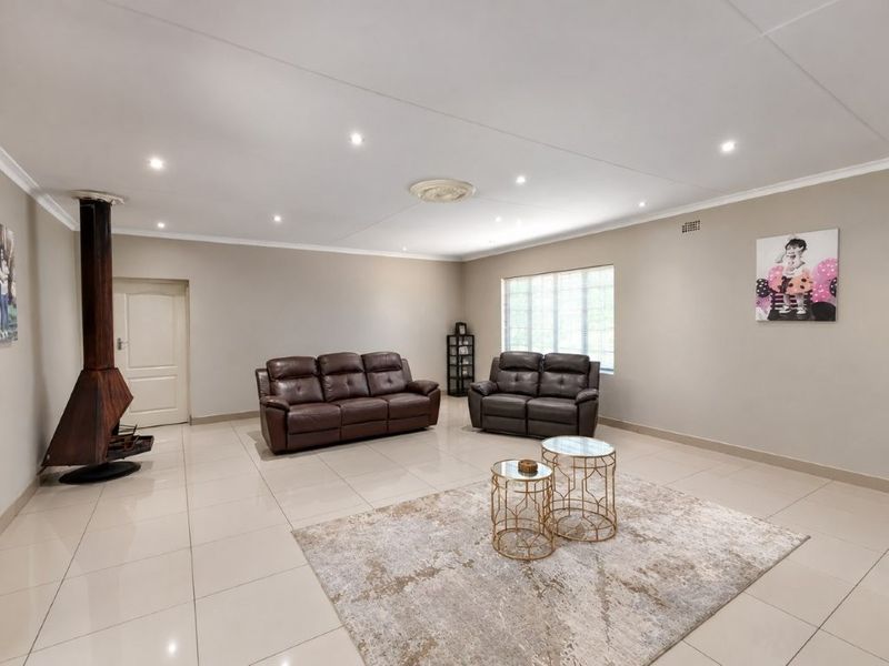 Spacious living room featuring neutral tiled flooring, recessed downlighting, and a distinctive freestanding fireplace, offering a clean and versatile layout.