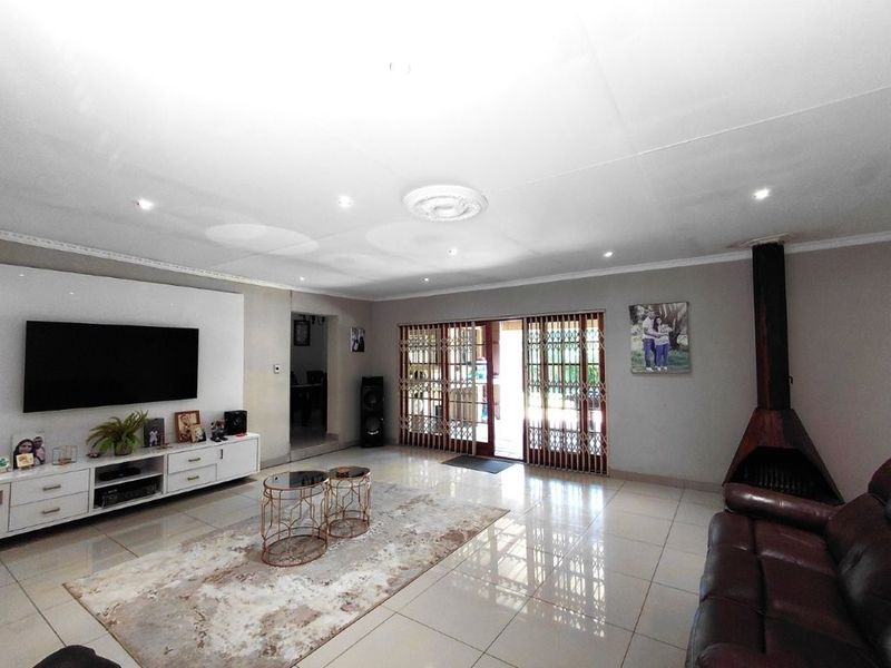 Spacious living room featuring tiled flooring, a modern freestanding fireplace, and large sliding glass doors with security gates leading to the outdoor area.