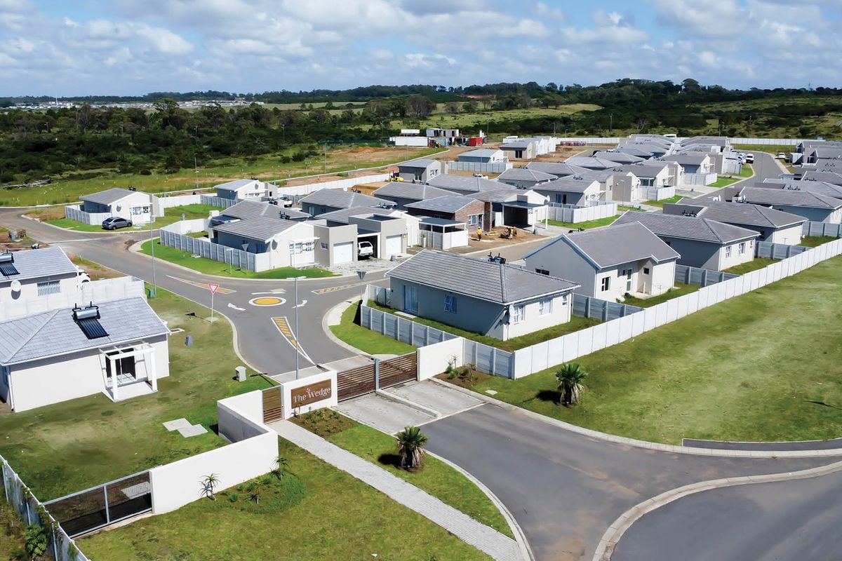 Aerial view of a modern residential estate development featuring multiple detached houses, paved internal roads, and a secure gated entrance.
