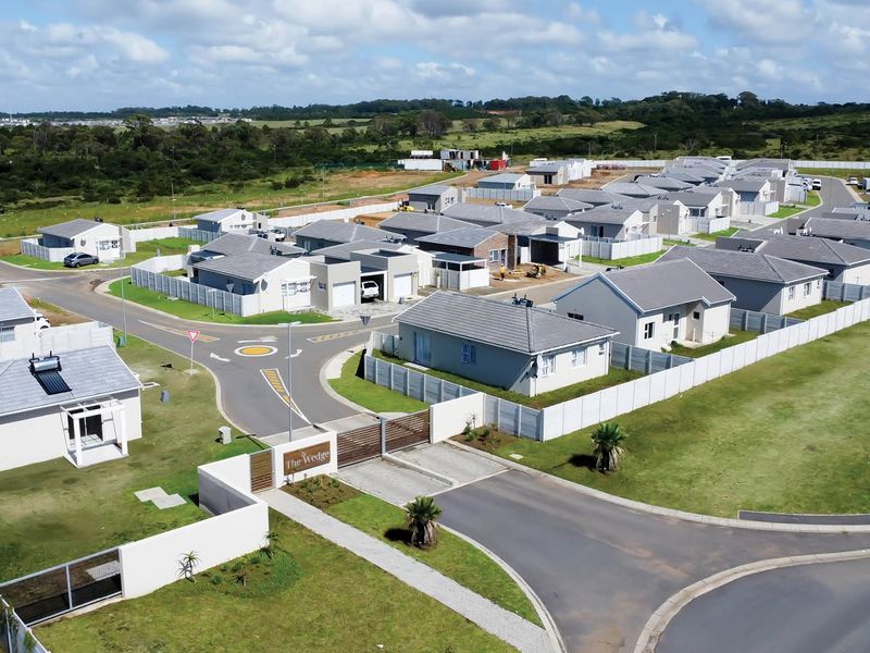Aerial view of a modern residential estate development featuring multiple detached houses, paved internal roads, and a secure gated entrance.