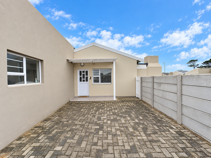 Front exterior view of the property featuring a paved driveway, a covered entrance porch, and a secure precast concrete boundary wall.