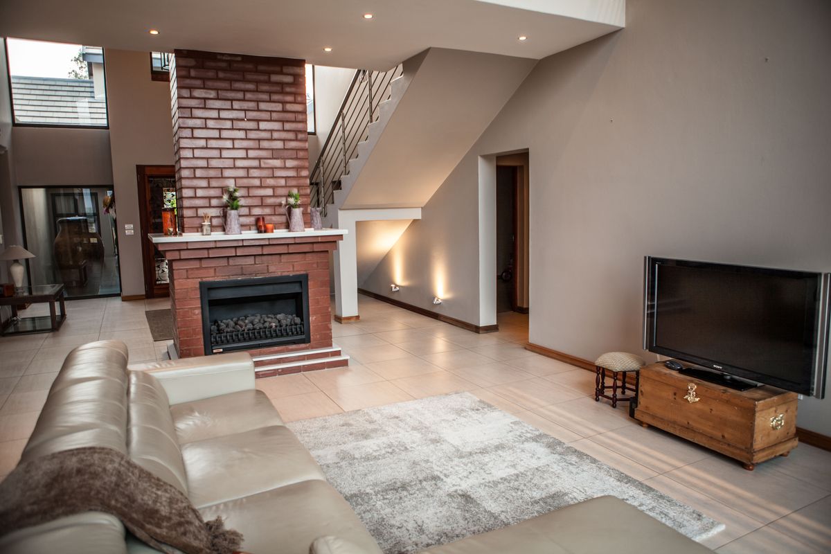 Spacious living room featuring a prominent brick fireplace, tiled flooring, and an open staircase leading to the upper level.