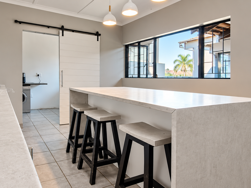 Modern kitchen featuring a large stone island, built-in microwave, gas hob, and a sliding barn door leading to a scullery area.