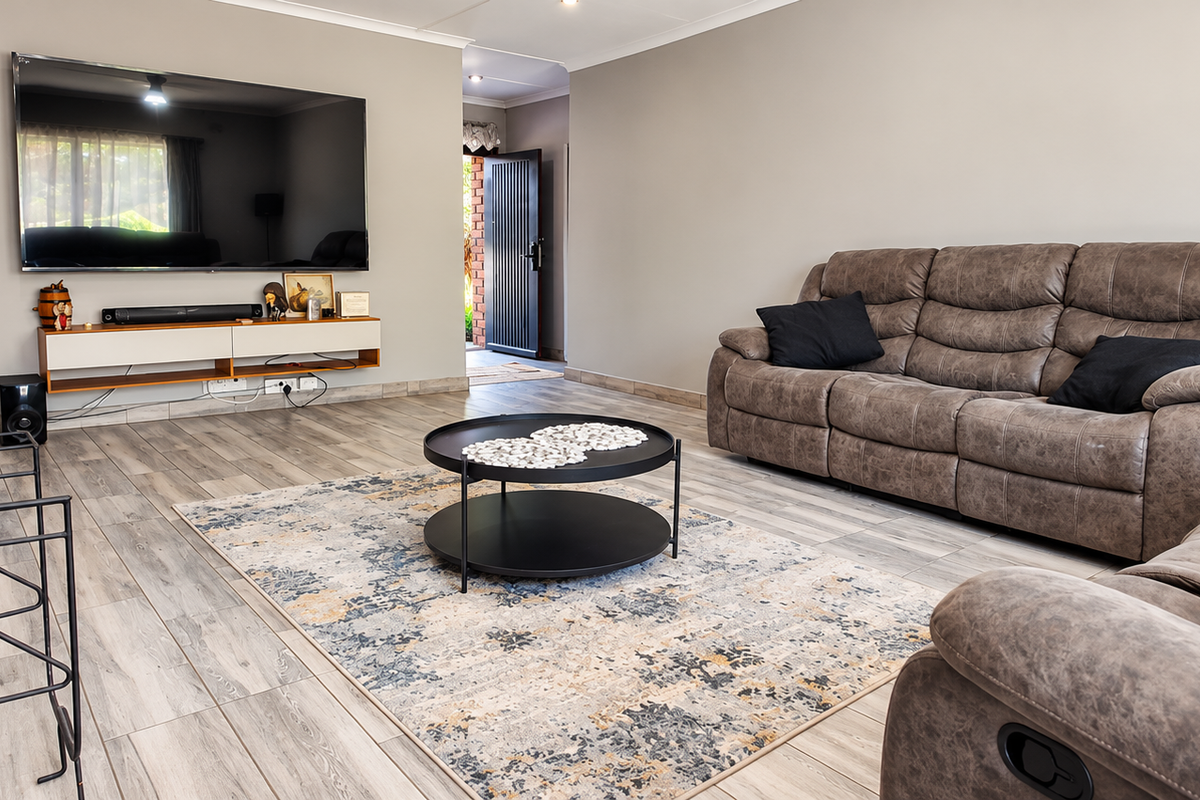 A well-maintained living room featuring wood-look tile flooring, a stone fireplace, and neutral wall tones, providing a comfortable and inviting space.
