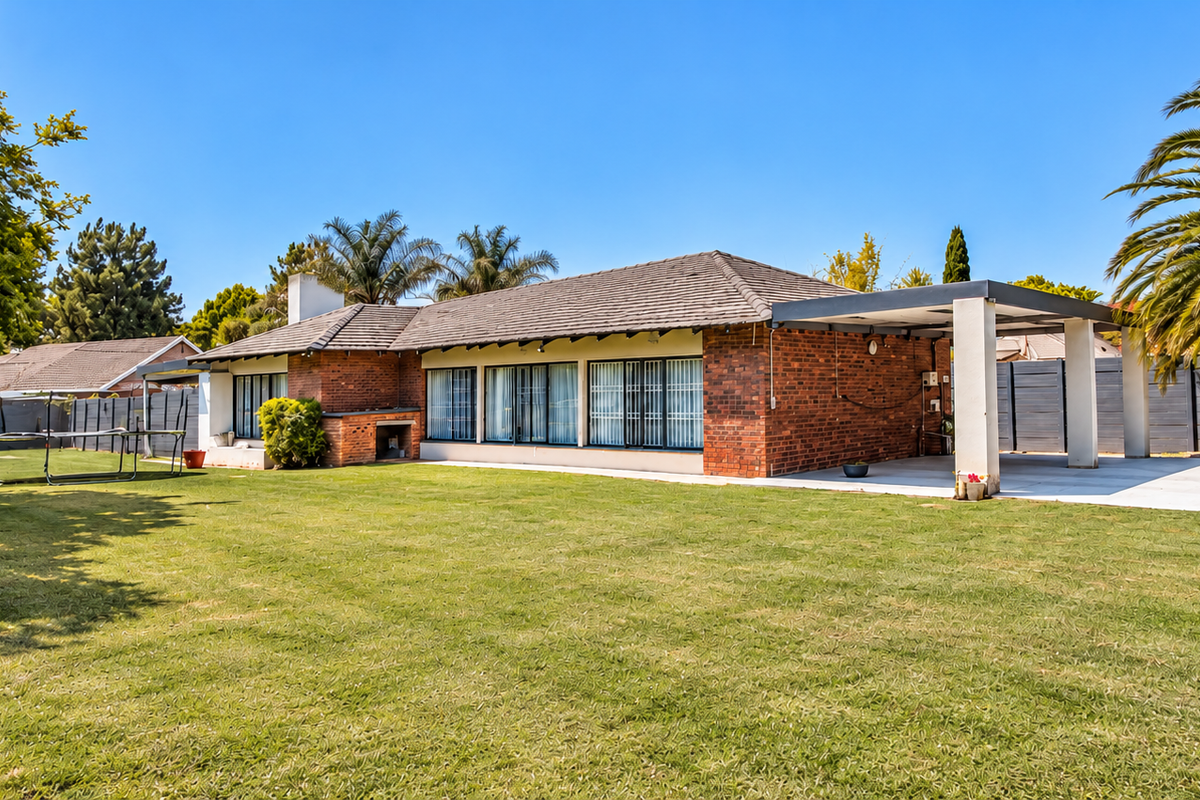 Spacious rear garden featuring a brick-faced house with a covered patio, built-in braai area, and a large lawn.