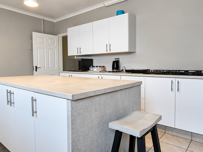 Modern kitchen featuring a central island, white cabinetry, gas hob, and neutral tiled flooring, offering a clean and functional workspace.