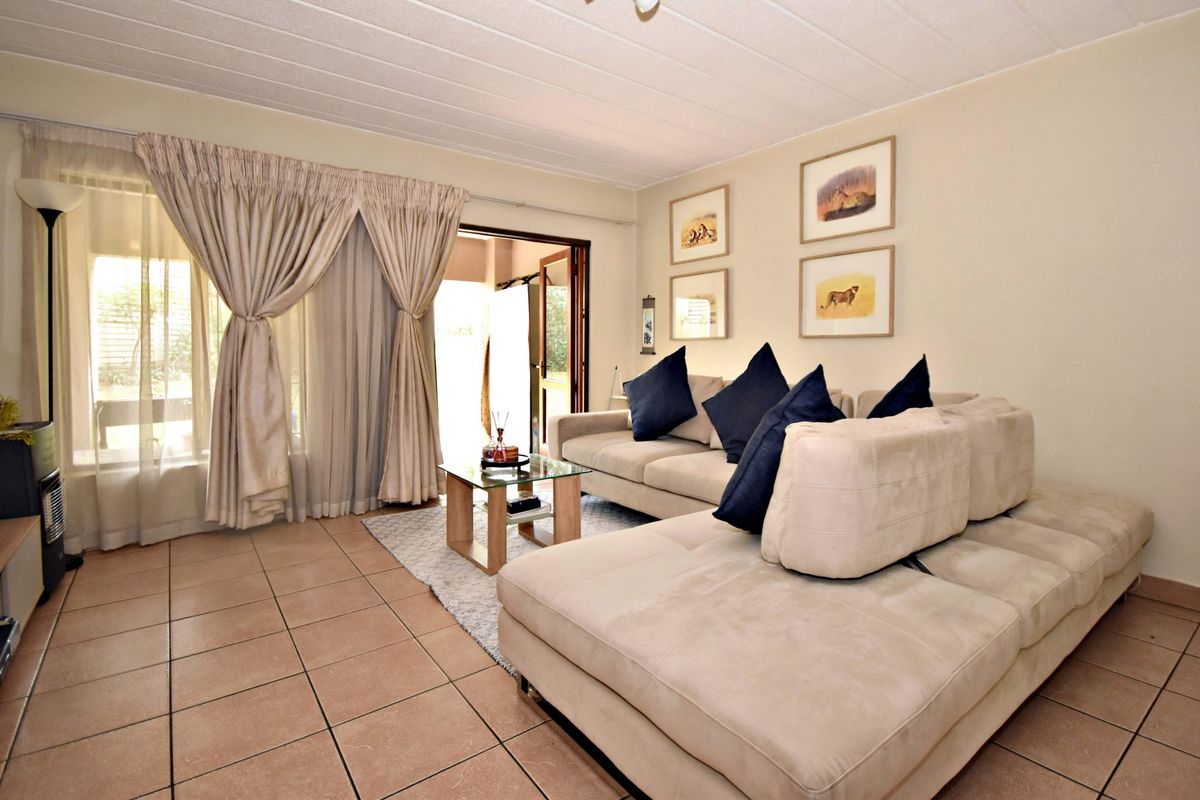 A comfortable living room featuring tiled flooring and a sliding glass door that provides access to the outdoor area.