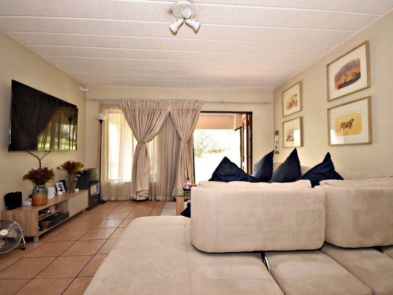 A comfortable living room featuring tiled flooring, neutral walls, and a sliding glass door providing access to the outdoor area.