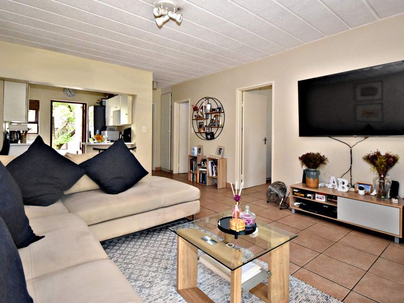 Open plan living area featuring tiled flooring and a textured ceiling, with direct access to the kitchen and adjacent rooms.
