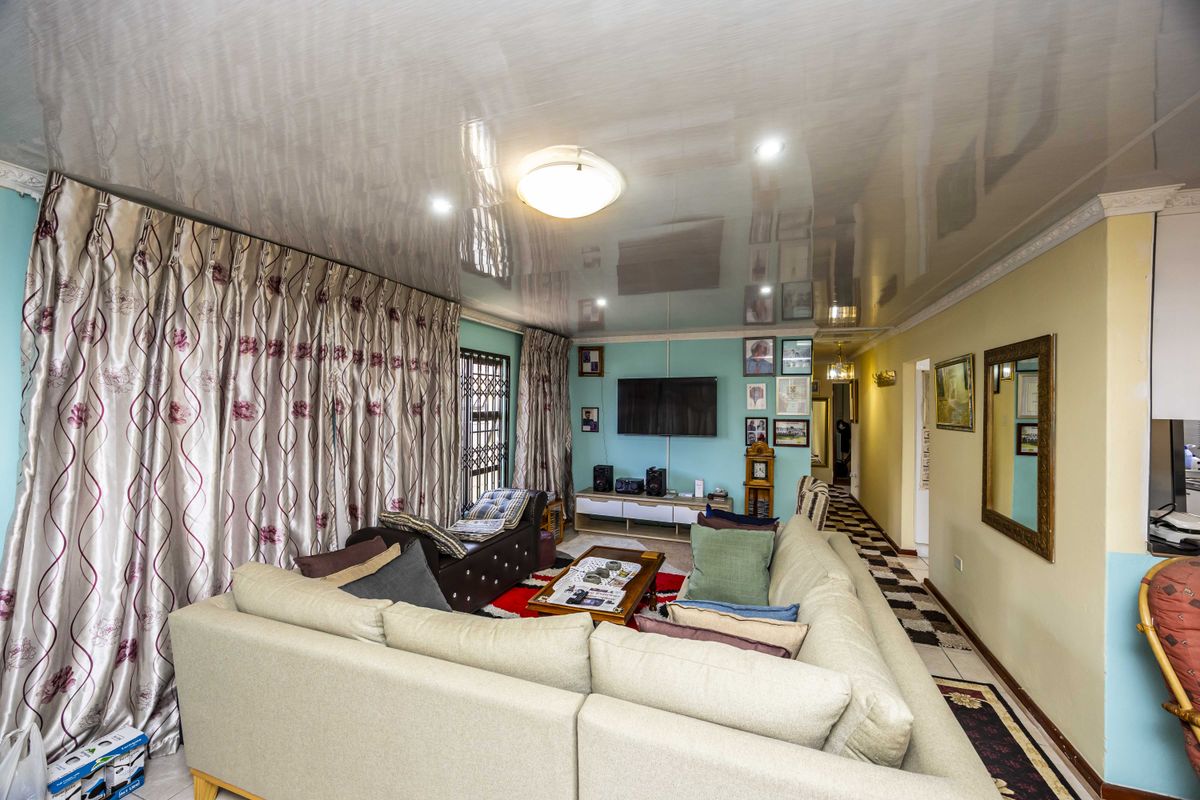 A living room featuring a glossy ceiling, tiled flooring, and a security gate, offering a functional space with potential for modern updates.