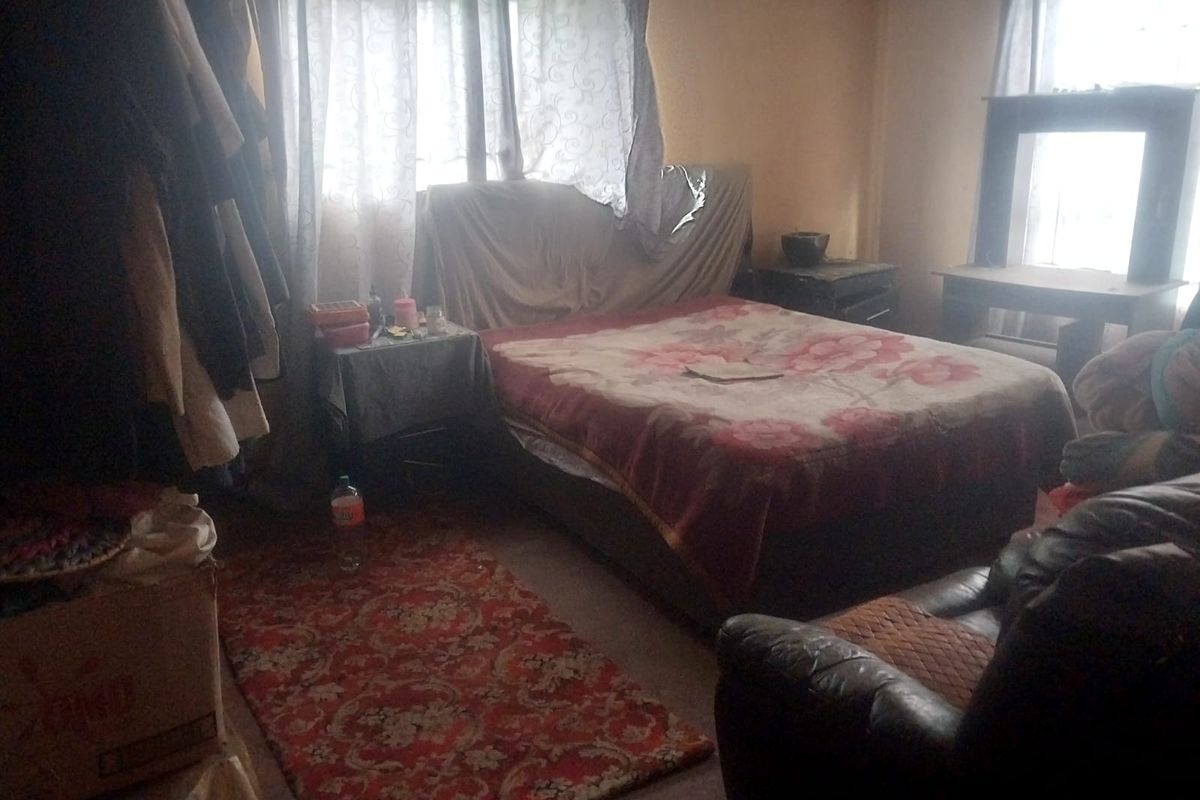 A bedroom featuring natural light from windows with curtains, providing a functional sleeping space.