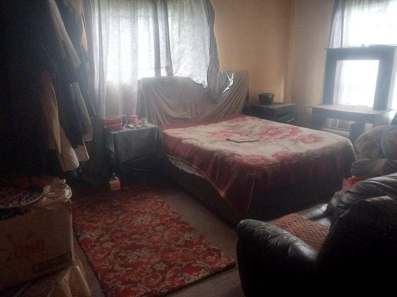 A bedroom featuring natural light from windows with curtains, providing a functional sleeping space.