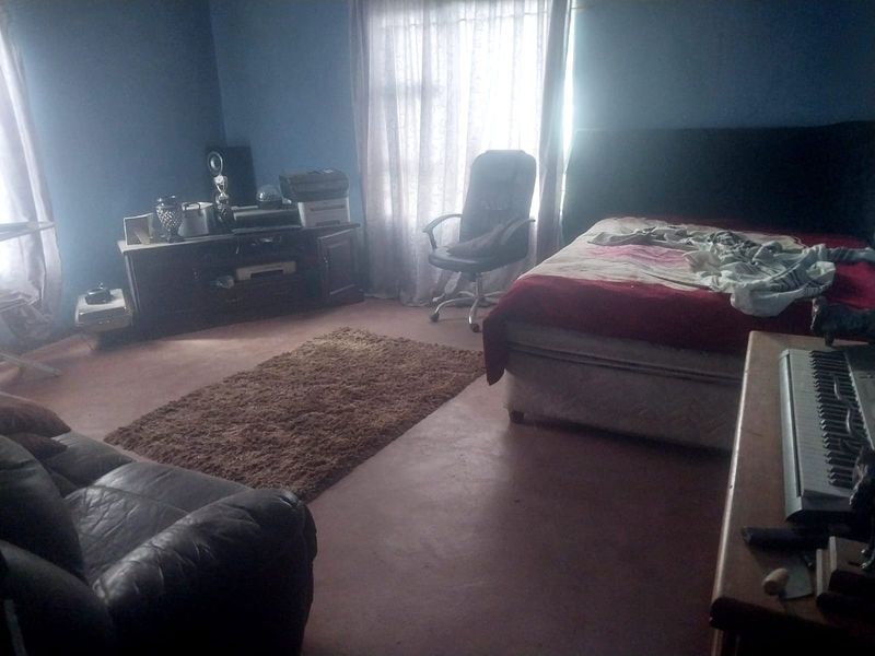 A bedroom featuring blue painted walls and natural light from a window with curtains.