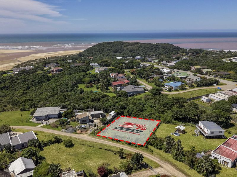 Aerial view of a vacant residential plot situated in a coastal neighborhood, offering proximity to the beach and surrounding natural landscape.