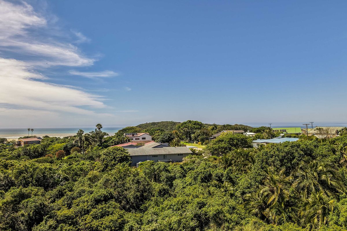 A scenic elevated view overlooking a lush coastal landscape with surrounding residential properties and the ocean in the distance.