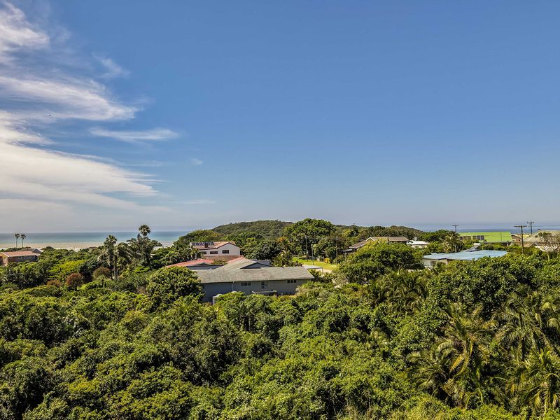 A scenic elevated view overlooking a lush coastal landscape with surrounding residential properties and the ocean in the distance.