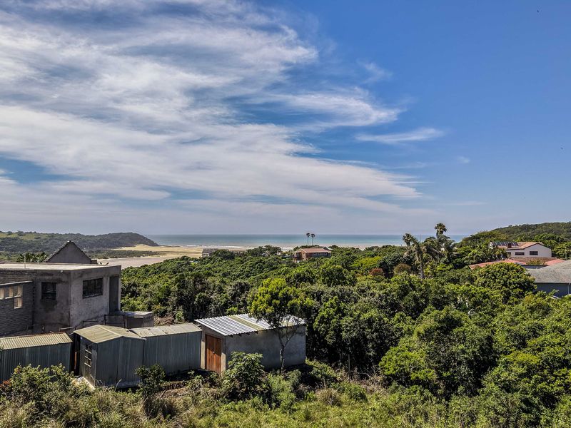 An elevated view overlooking a coastal landscape with lush vegetation and distant ocean horizon.