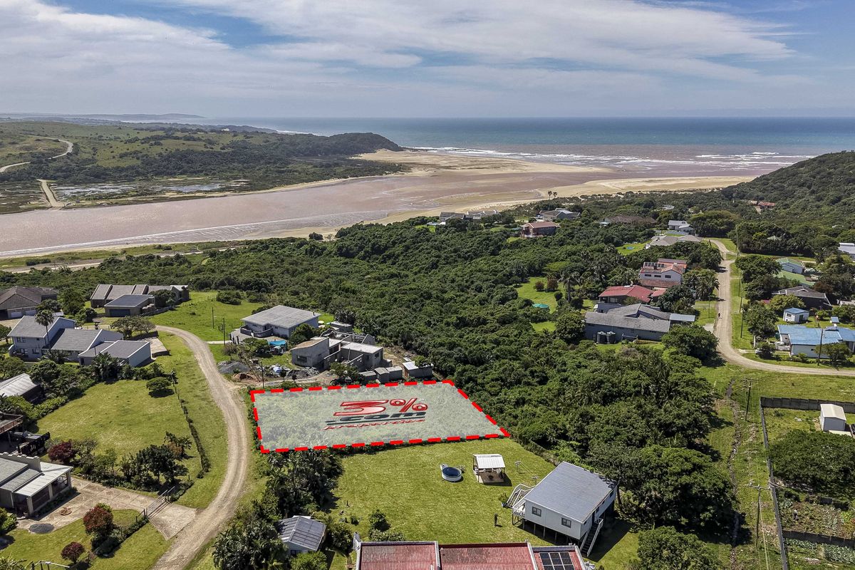 Aerial view of a vacant residential plot situated in a coastal area with surrounding natural vegetation and nearby residential properties.