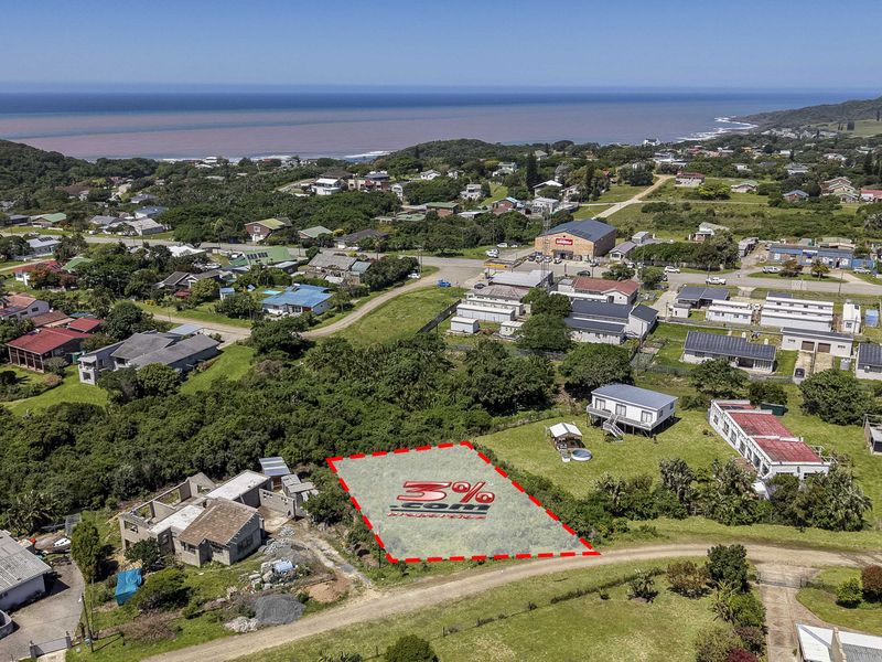 An aerial view of a vacant residential plot situated in a coastal neighborhood, highlighting the surrounding landscape and proximity to the ocean.