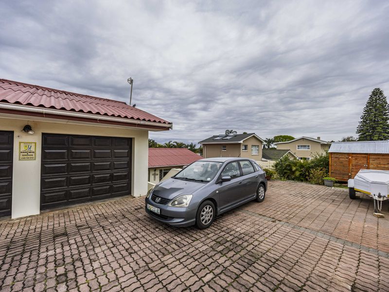 A paved driveway leading to a garage with a metal roof, providing ample off-street parking space.