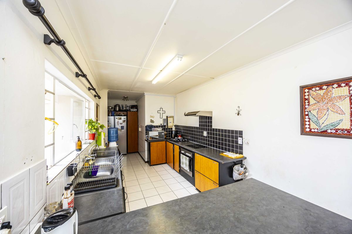 Functional kitchen featuring built-in cabinetry, laminate countertops, a stainless steel sink, and integrated cooking appliances with a tiled backsplash.