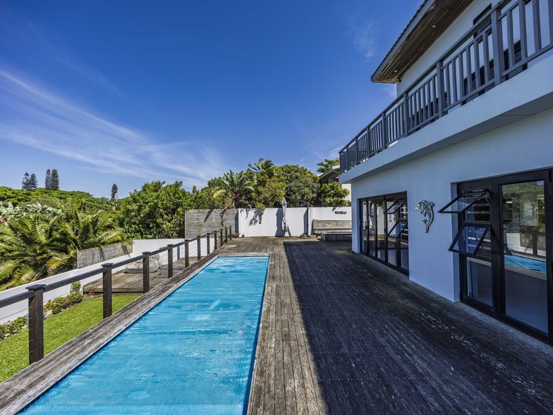 Outdoor pool area featuring extensive wooden decking, a swimming pool with cover, and direct access to the home via large sliding glass doors.