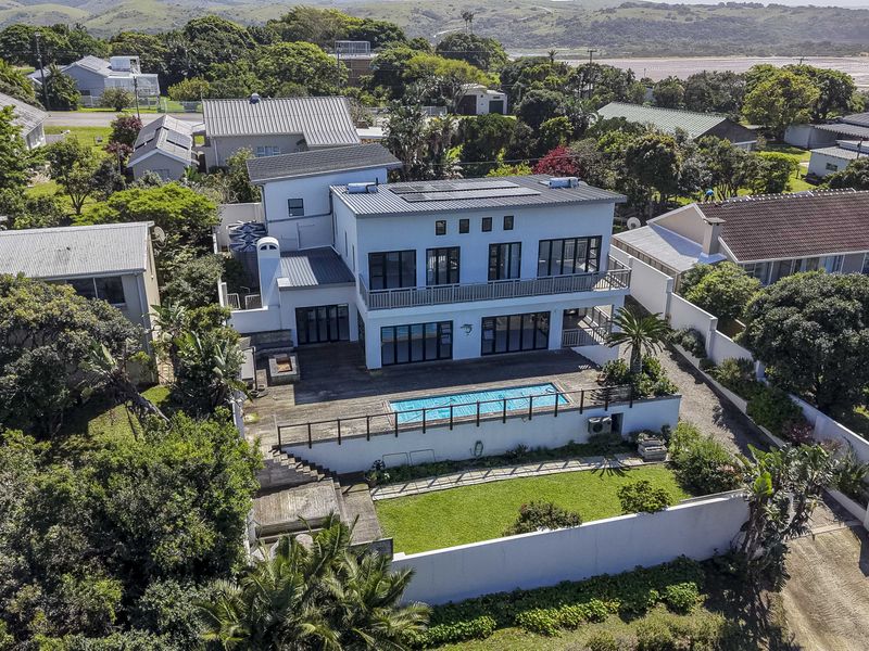 Aerial view of a multi-story residential property featuring a swimming pool, timber deck, balcony, and solar panels, set within a landscaped coastal neighborhood.