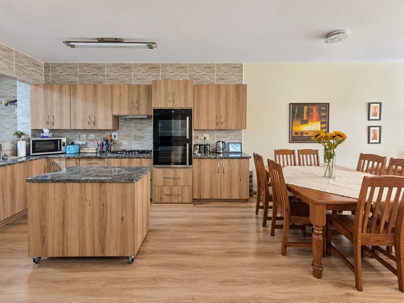 Spacious open-plan kitchen and dining area featuring wood-look cabinetry, granite countertops, built-in double oven, and durable laminate flooring.