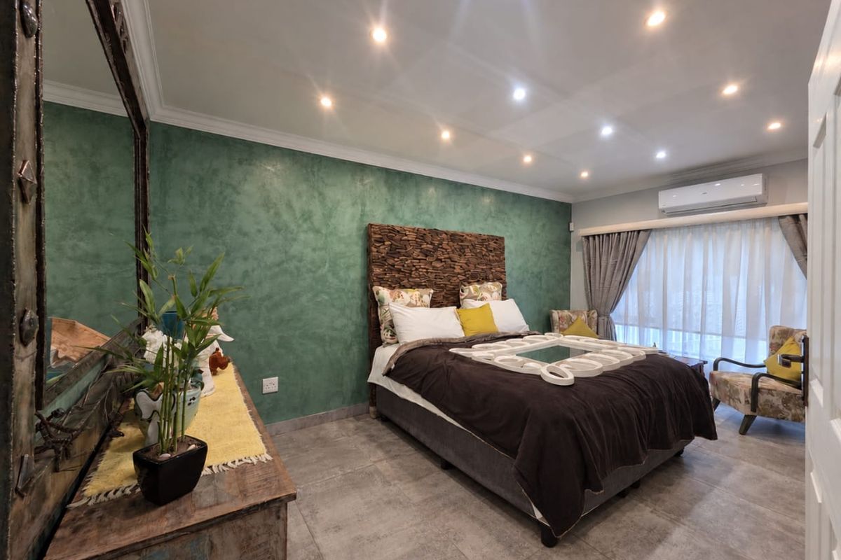 A well-maintained bedroom featuring tiled flooring, recessed downlighting, crown molding, and a wall-mounted split-system air conditioning unit.