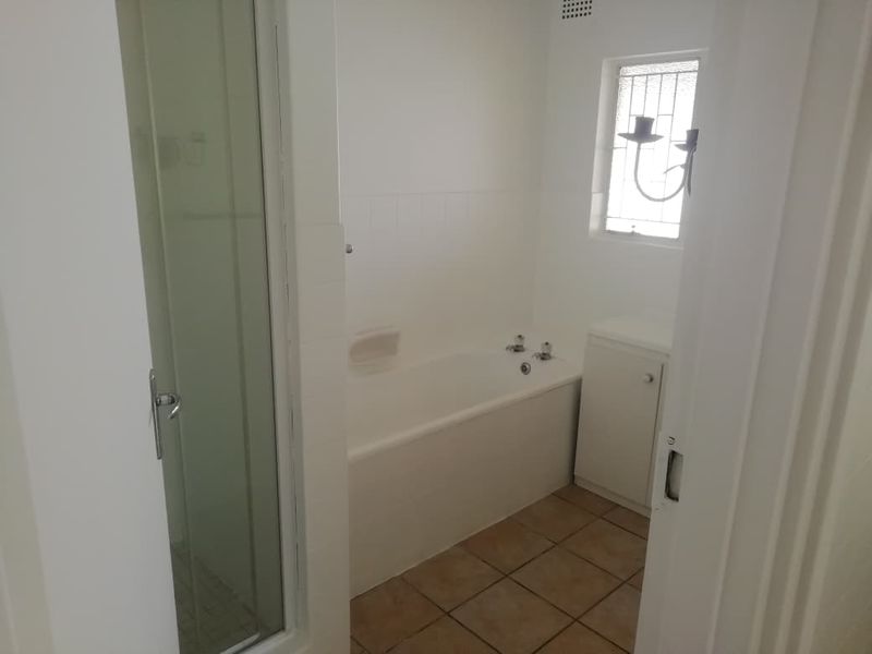 A functional bathroom featuring a bathtub, separate shower enclosure, tiled flooring, and a built-in vanity cabinet.