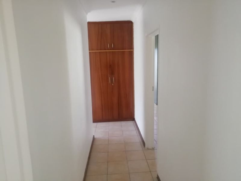 A functional hallway featuring tiled flooring and built-in wooden storage cupboards, providing clean and simple circulation space within the home.