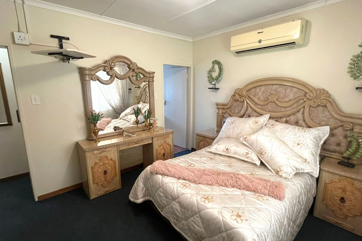 A carpeted bedroom featuring a wall-mounted split-system air conditioner and classic coving detail.