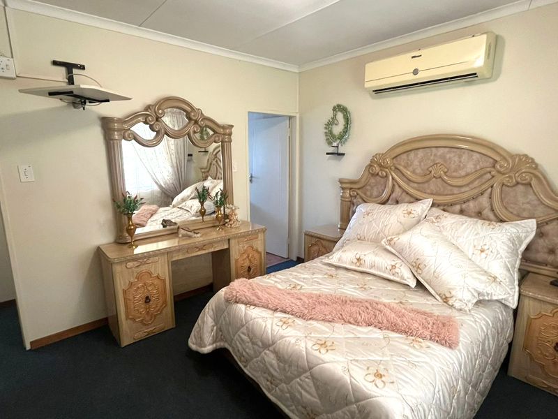 A carpeted bedroom featuring a wall-mounted split-system air conditioner and classic coving detail.