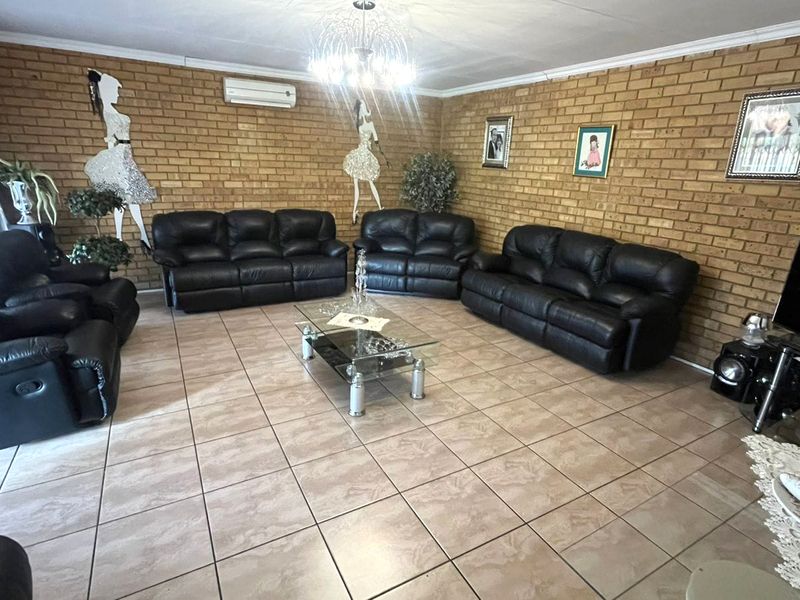 Spacious living room featuring exposed brick walls, tiled flooring, and a wall-mounted air conditioning unit.