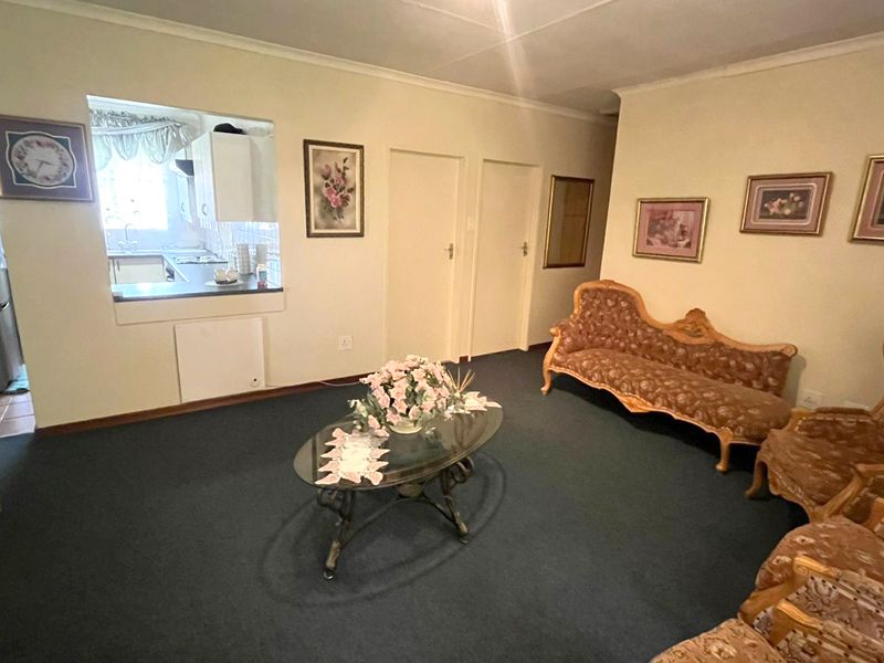 A living room featuring carpeted flooring and a serving hatch connecting to the kitchen area.