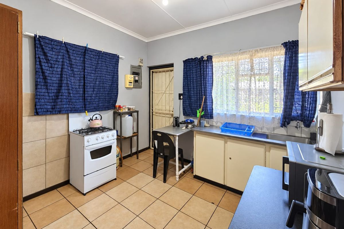 Functional kitchen featuring tiled flooring, built-in cabinetry, a stainless steel sink, and a gas stove with direct access to an exterior security door.