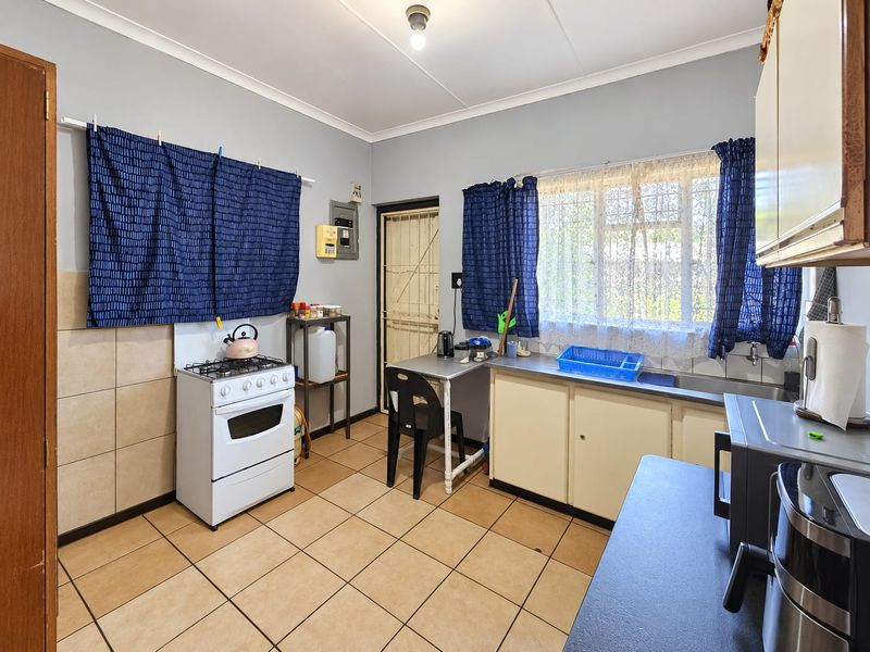 Functional kitchen featuring tiled flooring, built-in cabinetry, a stainless steel sink, and a gas stove with direct access to an exterior security door.