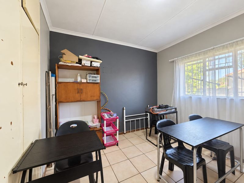 A bedroom featuring tiled flooring, built-in cupboards, and a window with security bars, offering a functional space ready for a modern update.