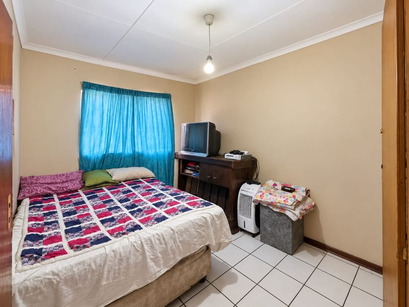 A functional bedroom featuring tiled flooring and coved ceilings, offering a neutral base ready for modern updates and personal styling.