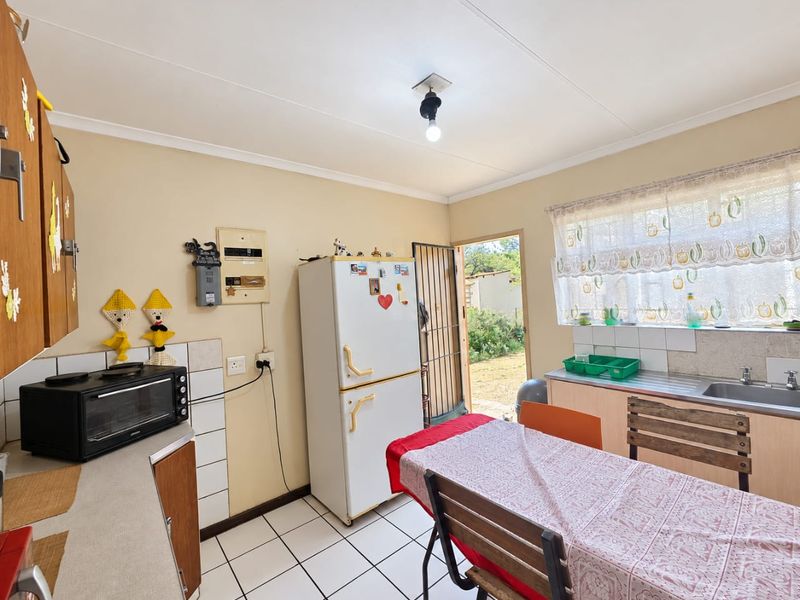 A functional kitchen featuring tiled flooring, built-in cabinetry, and a stainless steel sink, with direct access to the rear exterior.