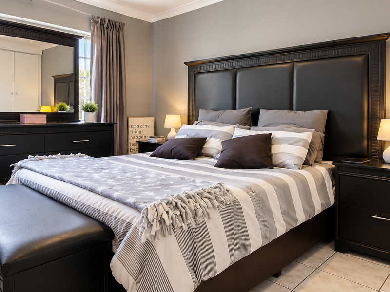 A well-maintained bedroom featuring tiled flooring, neutral wall tones, and built-in storage cabinetry.