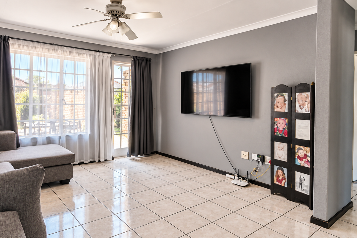 A well-maintained living room featuring neutral tiled flooring, a ceiling fan, and direct access to the outdoor area through a sliding glass door.